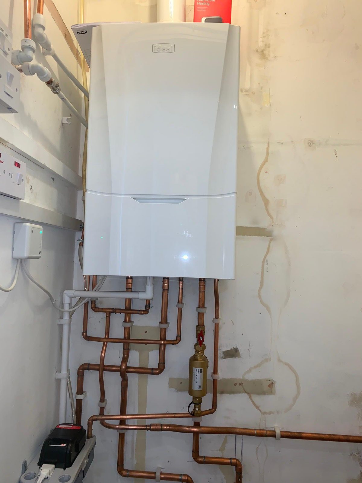 White boiler with copper pipework and a filter in a utility space