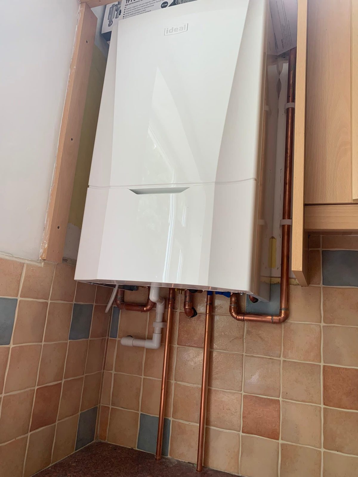 Boiler in a tiled kitchen corner with copper pipework