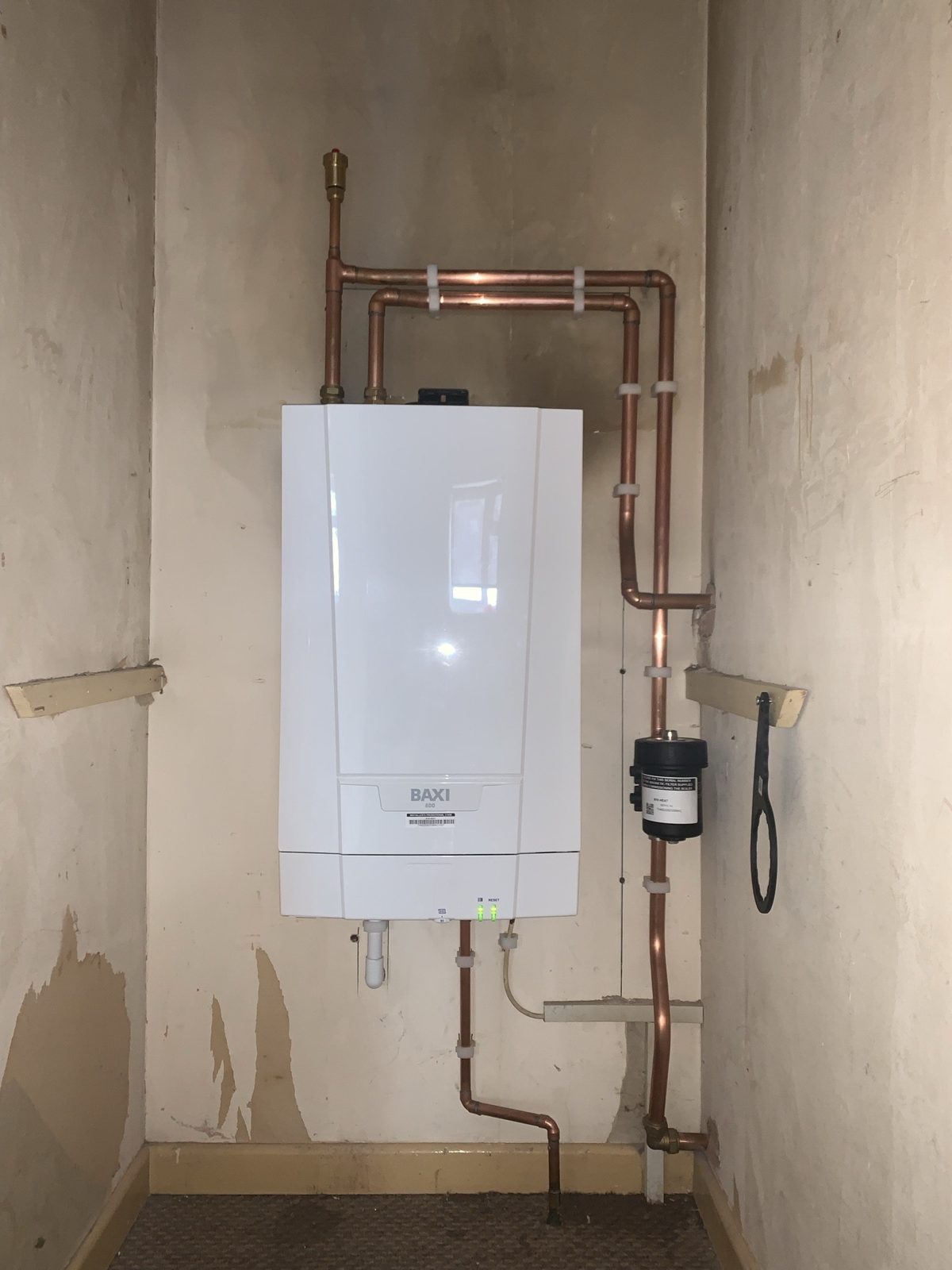 New boiler in a cupboard with copper pipework running up and across the wall