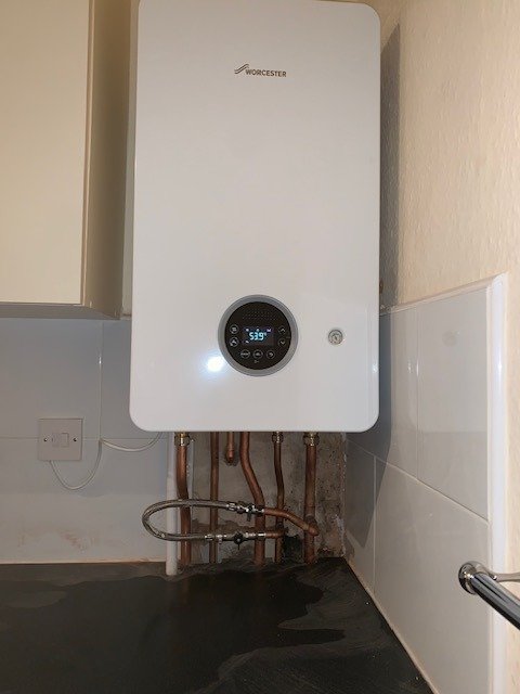 Boiler with a round display on a tiled kitchen wall