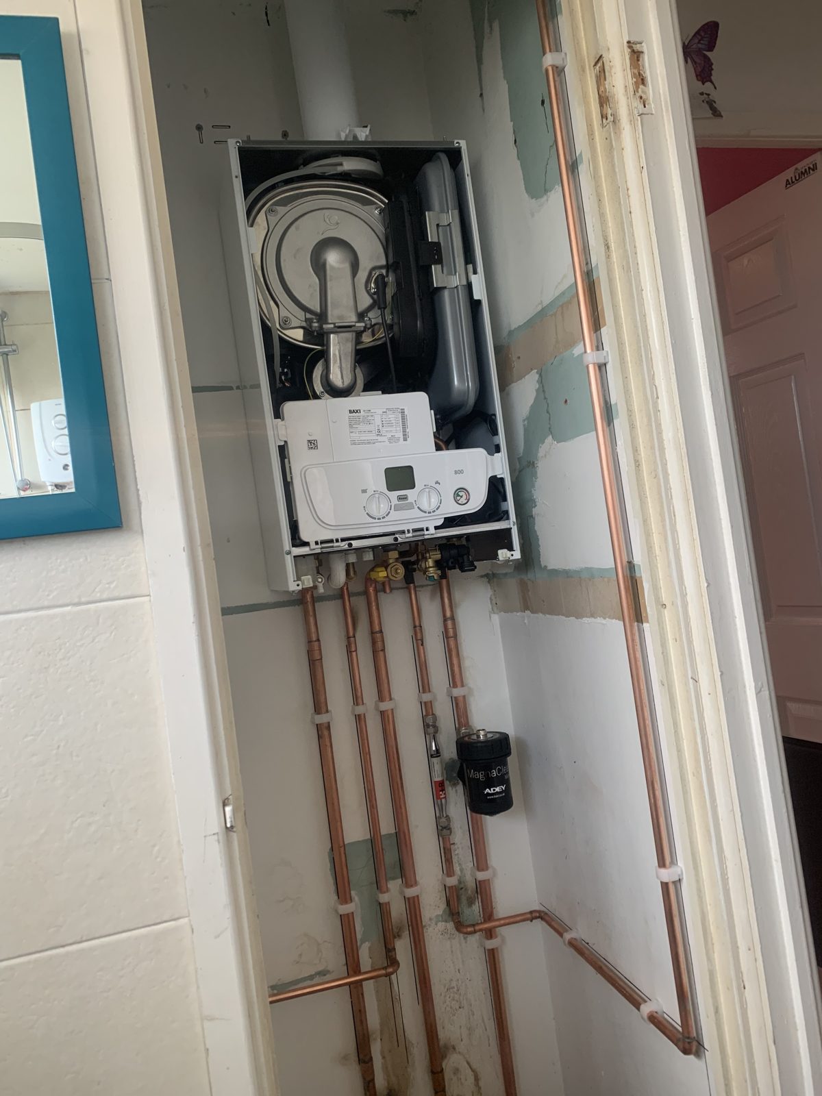 Boiler with its cover off during installation, new copper pipework below