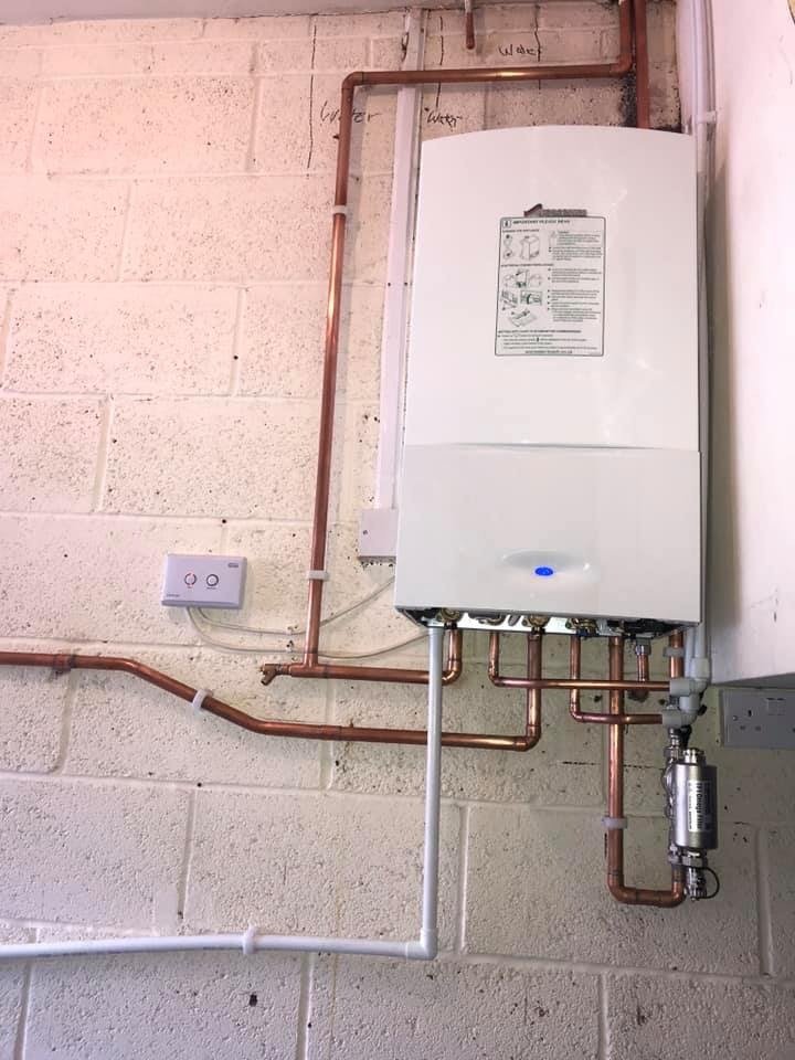 Boiler on a painted block wall with copper pipework and a filter