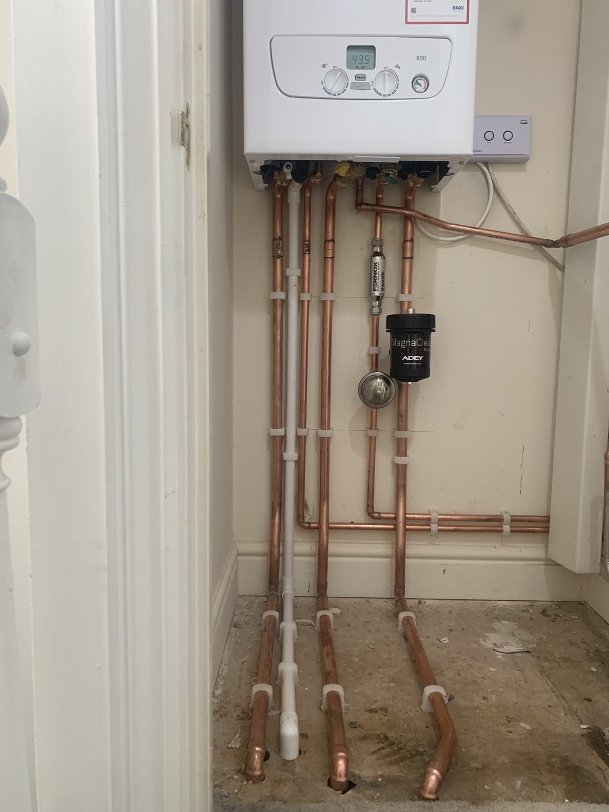 New copper pipework below a boiler in a cupboard
