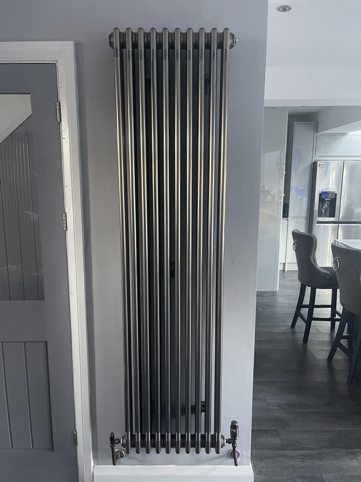 Tall vertical anthracite column radiator in a hallway
